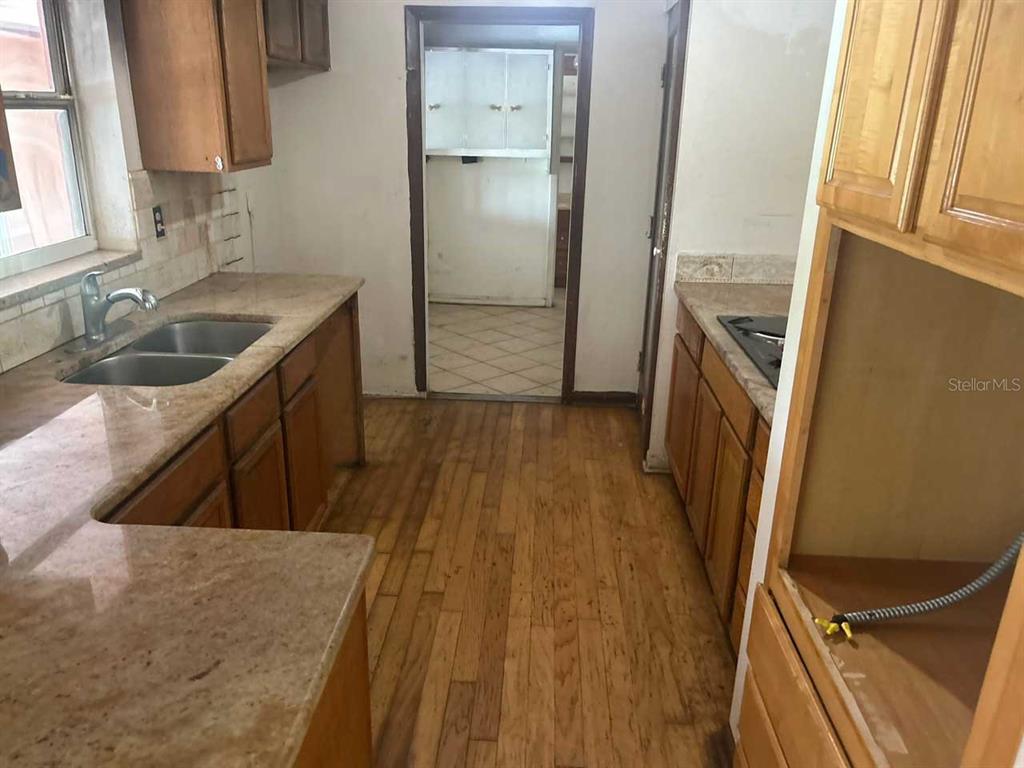 A kitchen features wood cabinets, granite countertops, a double sink, and hardwood flooring — 1749 HAVERHILL DRIVE, DELTONA, FL