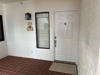 A white front door with a side window and a tiled porch entrance — 1425 GULF OF MEXICO DRIVE UNIT 308, LONGBOAT KEY, FL