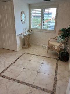 A tiled entryway features a decorative floor inlay, a glass-topped console table, and a wicker chair — 1425 GULF OF MEXICO DRIVE UNIT 308, LONGBOAT KEY, FL
