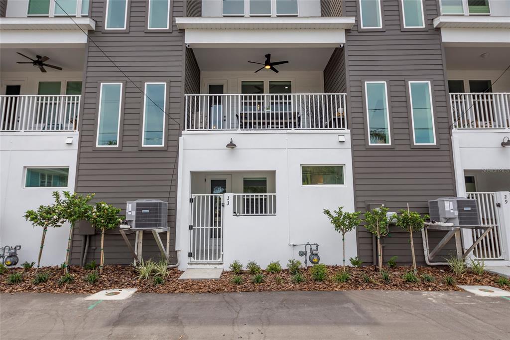 The exterior of a multi-story townhouse features dark gray siding, white trim, and a balcony — 33 29TH STREET N, ST PETERSBURG, FL
