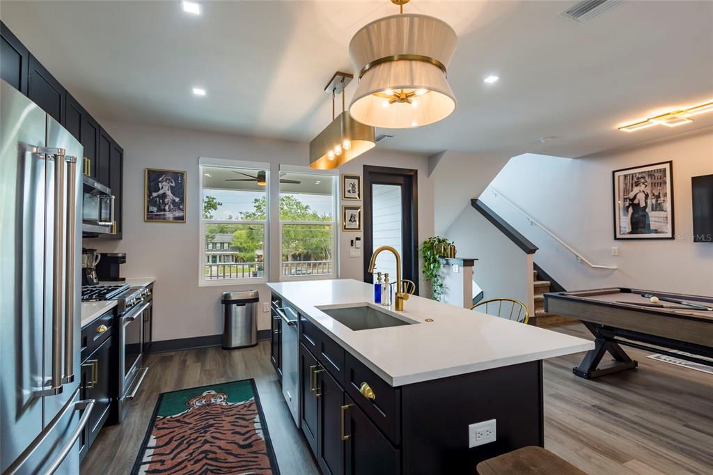 A kitchen with dark cabinets, a white island, and a pool table in the adjacent area — 33 29TH STREET N, ST PETERSBURG, FL