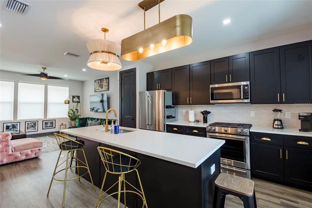 A modern kitchen features dark cabinetry, a white quartz island, and gold pendant lighting — 33 29TH STREET N, ST PETERSBURG, FL