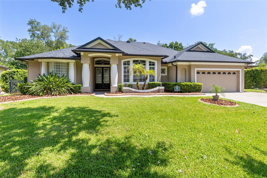 A single-story suburban house with a tan stucco exterior, dark roof, and two-car garage — 341 VERACLIFF COURT, OVIEDO, FL