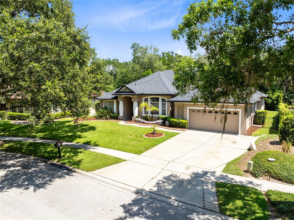 A single-story house with a tan exterior, a two-car garage, and a manicured front lawn — 341 VERACLIFF COURT, OVIEDO, FL