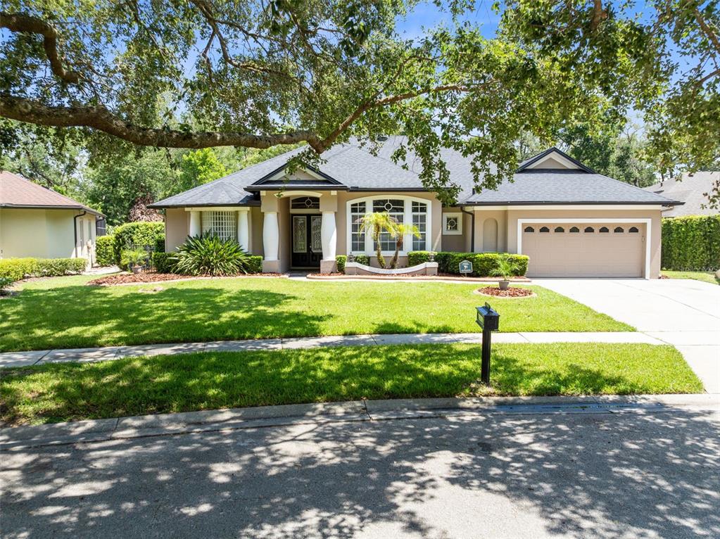A single-story house with a tan exterior, dark roof, and a two-car garage — 341 VERACLIFF COURT, OVIEDO, FL