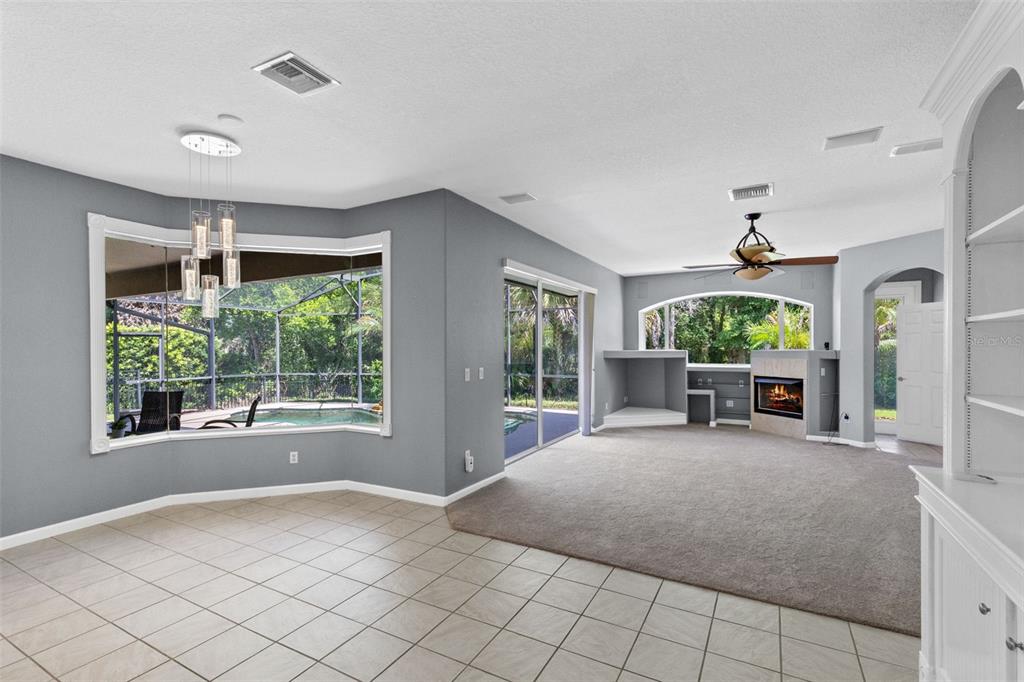 A living room with gray walls, carpeted flooring, a fireplace, and a view of a pool — 341 VERACLIFF COURT, OVIEDO, FL
