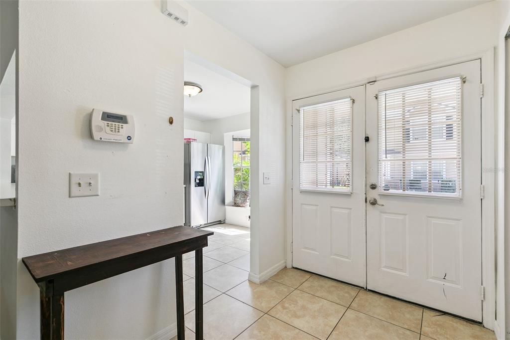 An entryway with tile flooring, a console table, and a white double door — 5989 BRAEMAR PLACE UNIT 102, ORLANDO, FL