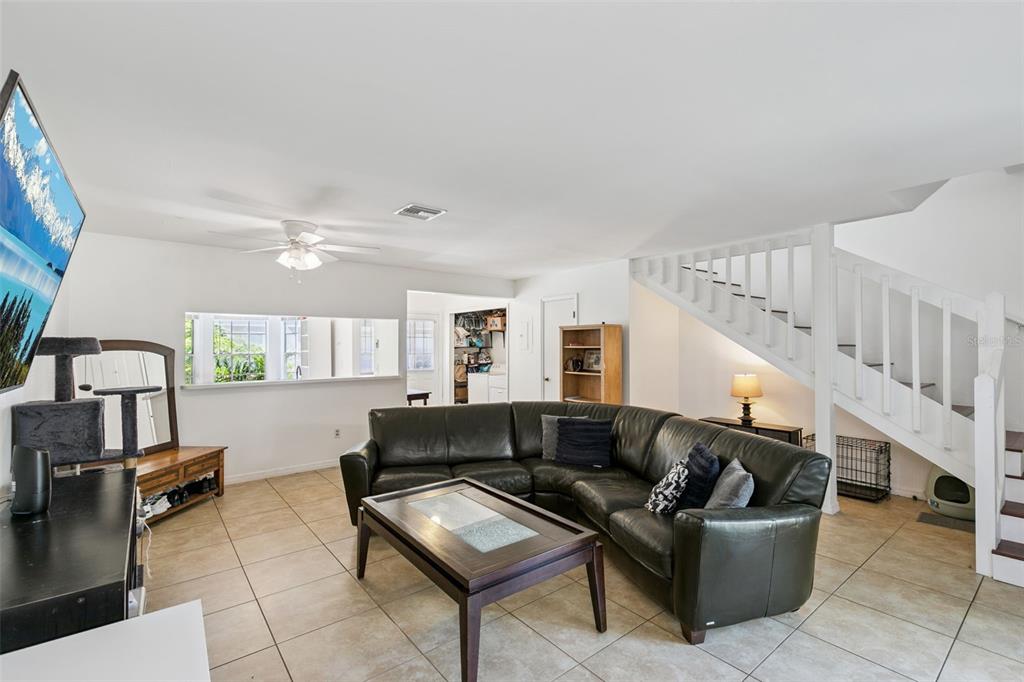 An empty room with white walls, tile flooring, a ceiling fan, and a wooden staircase — 5989 BRAEMAR PLACE UNIT 102, ORLANDO, FL