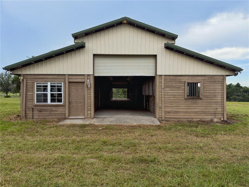 A barn with a metal roof, wood siding, a roll-up door, and a side entrance — 24087 TWISTER LANE, BROOKSVILLE, FL
