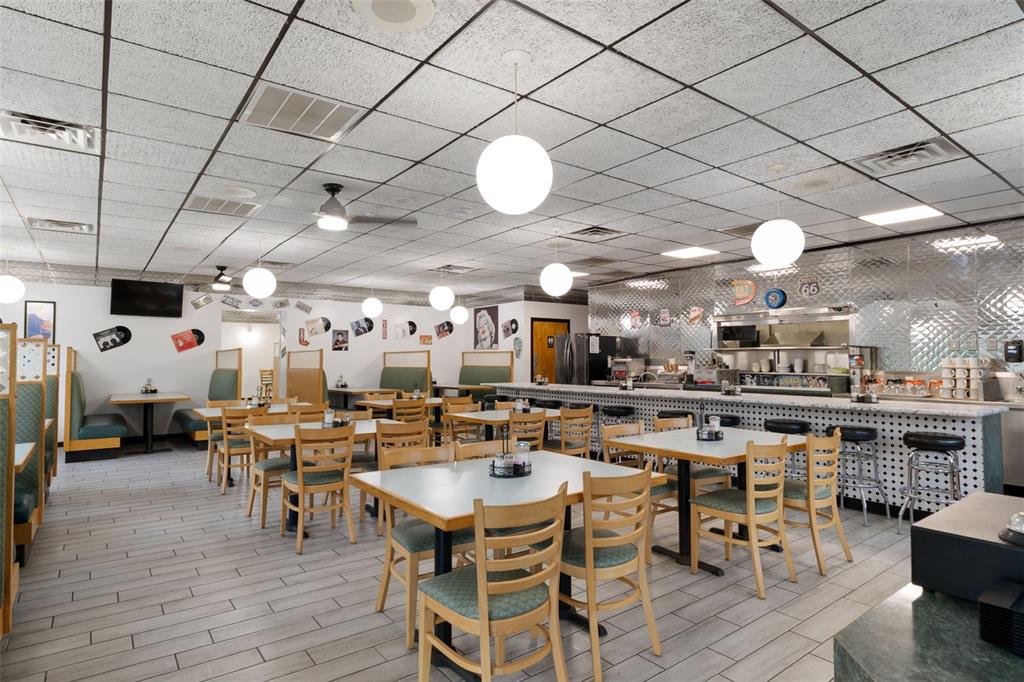 A restaurant dining room features tables, chairs, booths, a counter, and globe pendant lighting — 5300 E SILVER SPRINGS BOULEVARD UNIT B, SILVER SPRINGS, FL