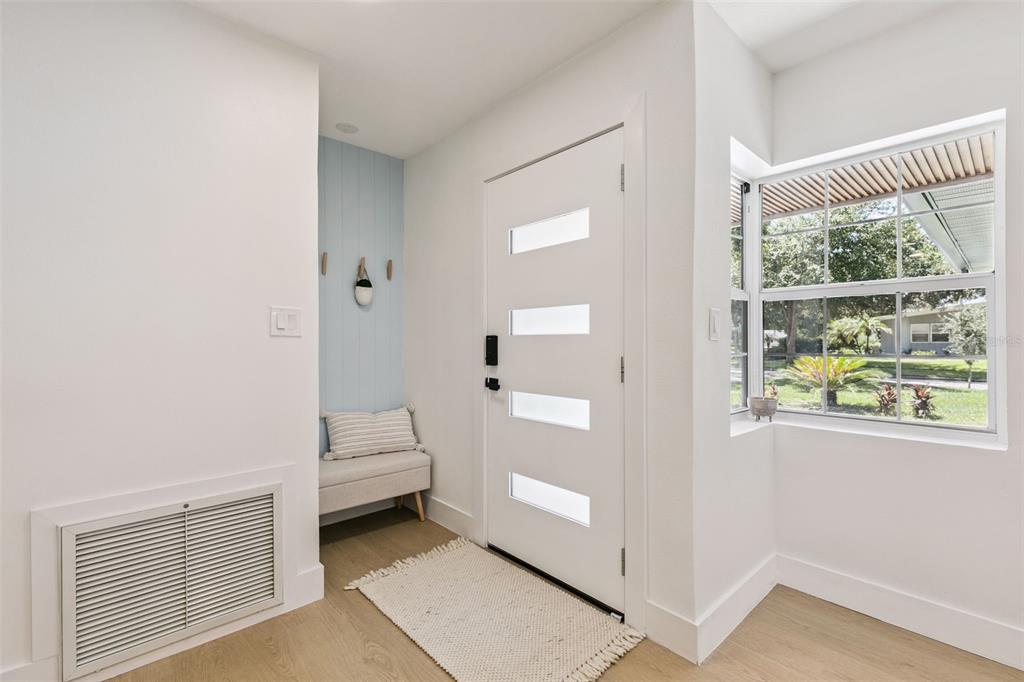 A bright entryway features a white front door, light wood flooring, and a small bench — 2833 PRINCE JOHN ROAD, WINTER PARK, FL