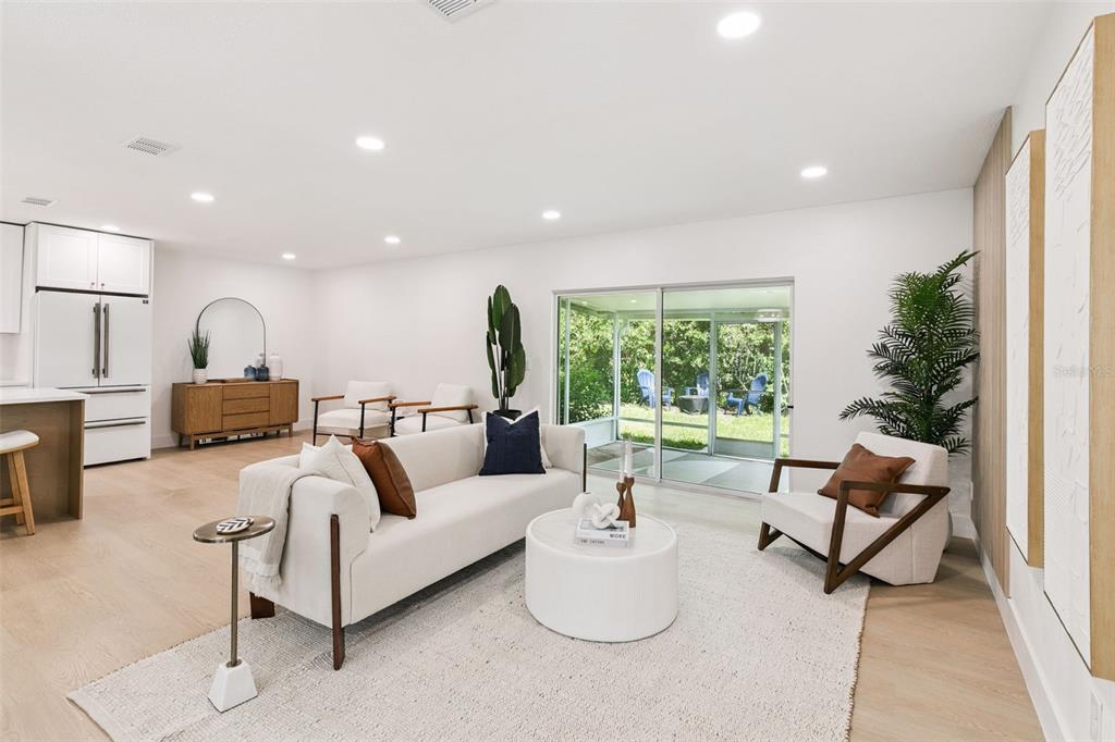 A bright living room features a white sofa, round coffee table, and sliding glass doors — 2833 PRINCE JOHN ROAD, WINTER PARK, FL