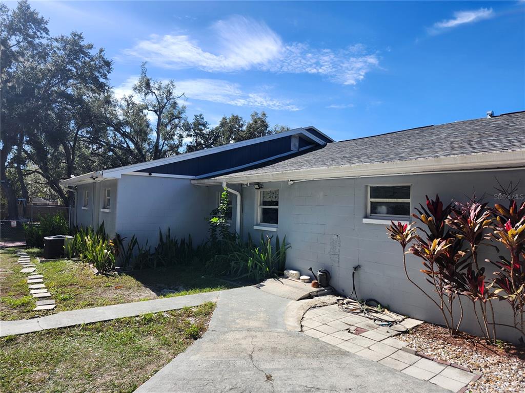 The exterior of a gray concrete block house features a dark blue gable and walkway — 10805 DESOTO ROAD, RIVERVIEW, FL