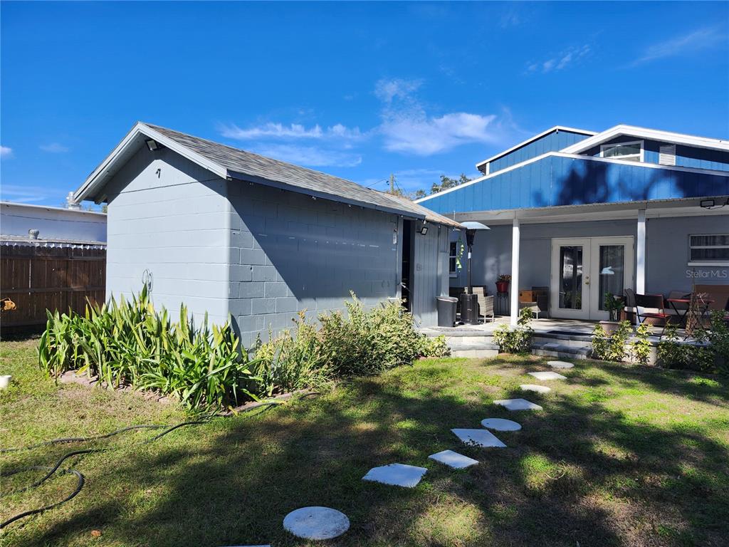 A gray concrete block shed stands in a backyard next to a blue house — 10805 DESOTO ROAD, RIVERVIEW, FL