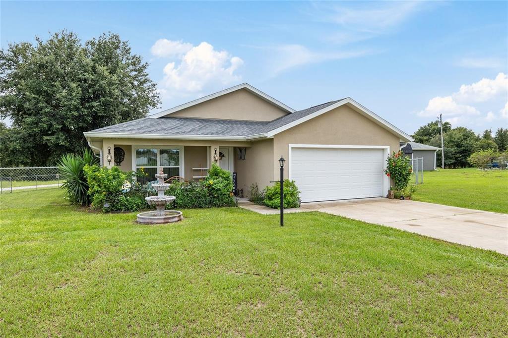 A single-story house with a beige exterior, a two-car garage, and a front yard fountain — 4660 SW 130TH STREET, OCALA, FL