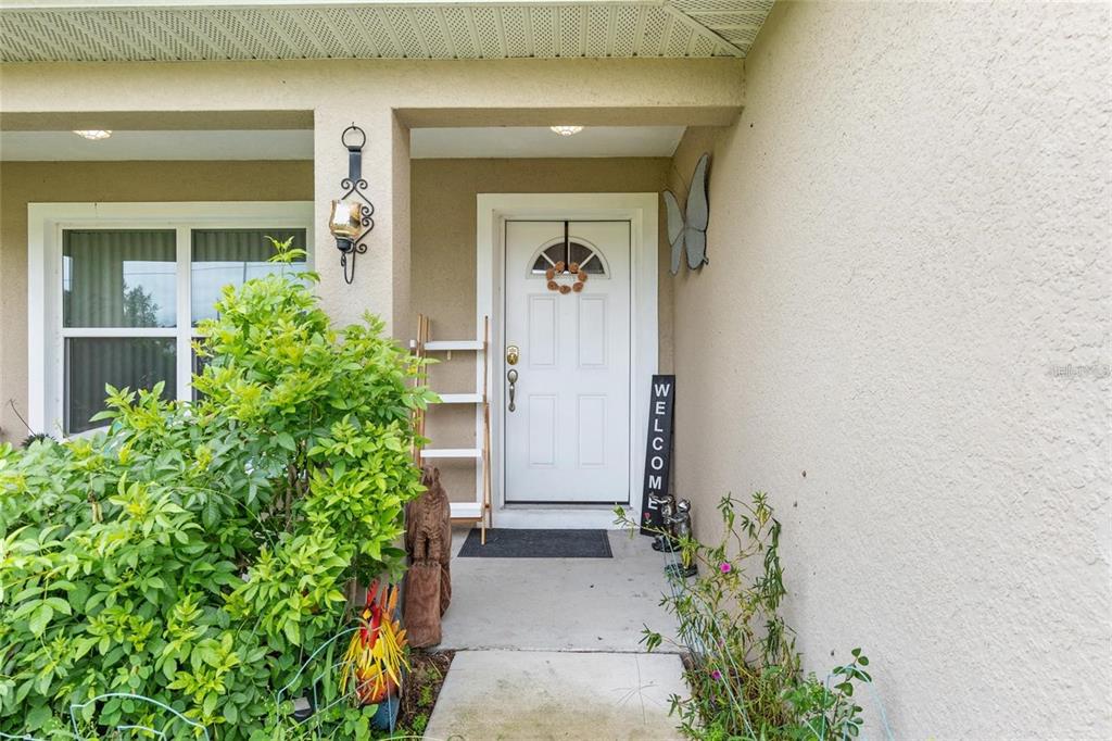 A front entryway features a white door, a welcome sign, and a small wooden shelf — 4660 SW 130TH STREET, OCALA, FL
