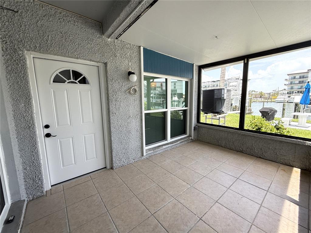 A tiled patio features a white door, a window, and a view of a waterfront — 179 MEDALLION BLVD UNIT C, MADEIRA BEACH, FL