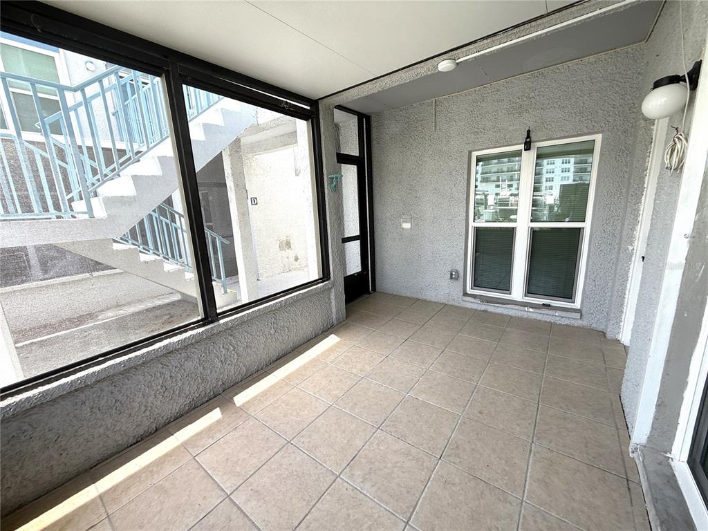 A covered patio features tiled flooring, stucco walls, and a large window looking outside — 179 MEDALLION BLVD UNIT C, MADEIRA BEACH, FL