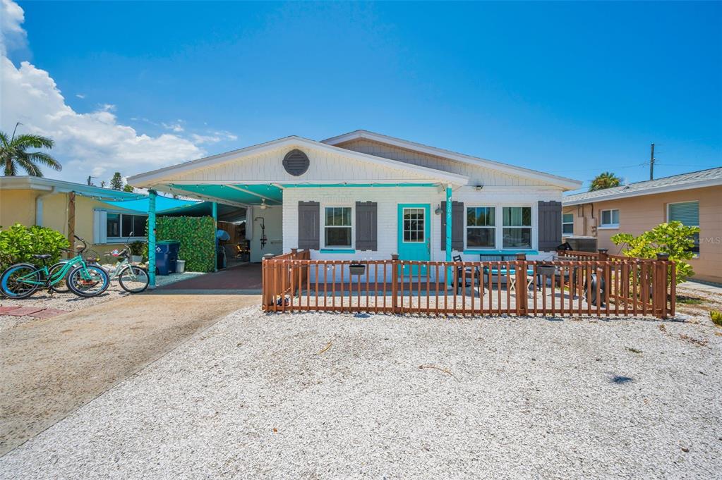 A white brick house with a turquoise door, a carport, and a fenced front patio — 305 15TH AVENUE, INDIAN ROCKS BEACH, FL