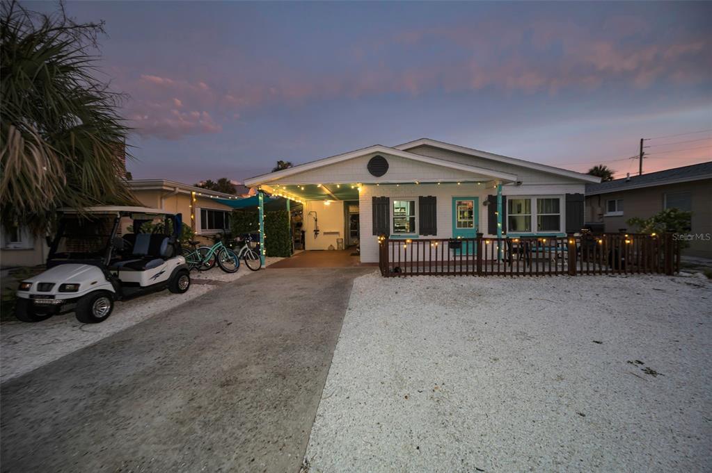 A single-story house with a white brick exterior, a wooden porch fence, and string lights — 305 15TH AVENUE, INDIAN ROCKS BEACH, FL