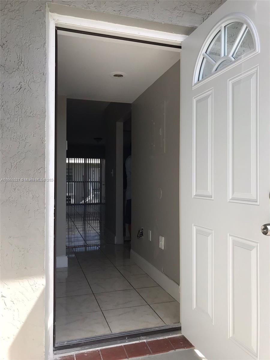 An open white door reveals a tiled entryway leading into a hallway with light-colored walls — 459 NE 210th Cir Ter # 17, Miami FL 33179, MIAMI, FL