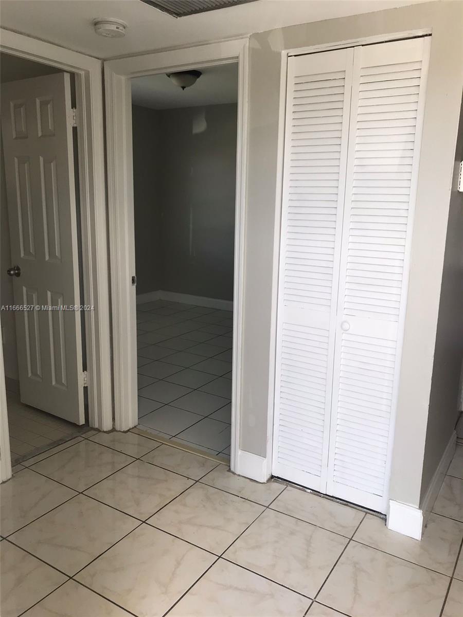 A hallway with tiled floors leads to a room featuring a louvered closet door — 459 NE 210th Cir Ter # 17, Miami FL 33179, MIAMI, FL
