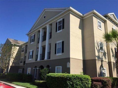A three-story apartment building with beige stucco walls, white columns, and a dark roof — 3583 CONROY ROAD UNIT 1135, ORLANDO, FL