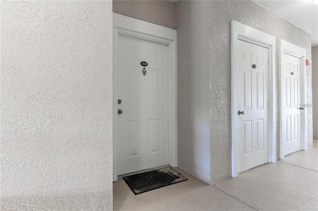 A hallway view showing three white apartment doors with unit numbers on a textured wall — 3583 CONROY ROAD UNIT 1135, ORLANDO, FL