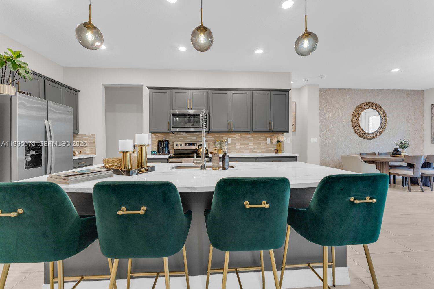 A modern kitchen features a large white island with green velvet stools and gray cabinetry — 8351 NW 7th Ct, Plantation FL 33324, PLANTATION, FL