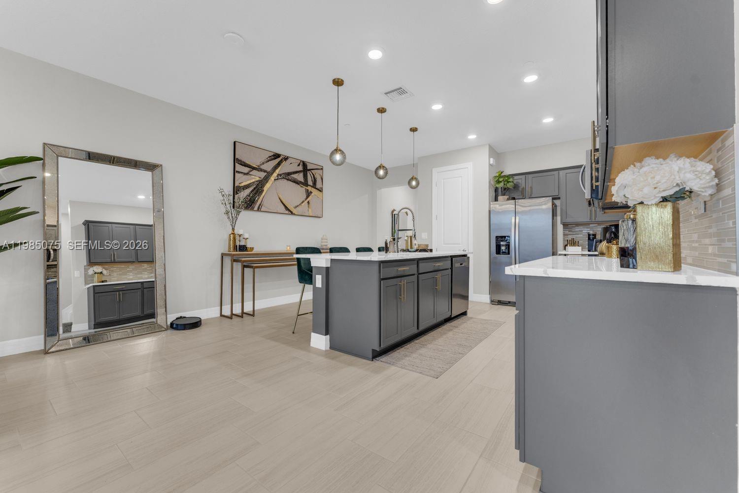 A modern kitchen features a large gray island, white countertops, and three hanging pendant lights — 8351 NW 7th Ct, Plantation FL 33324, PLANTATION, FL