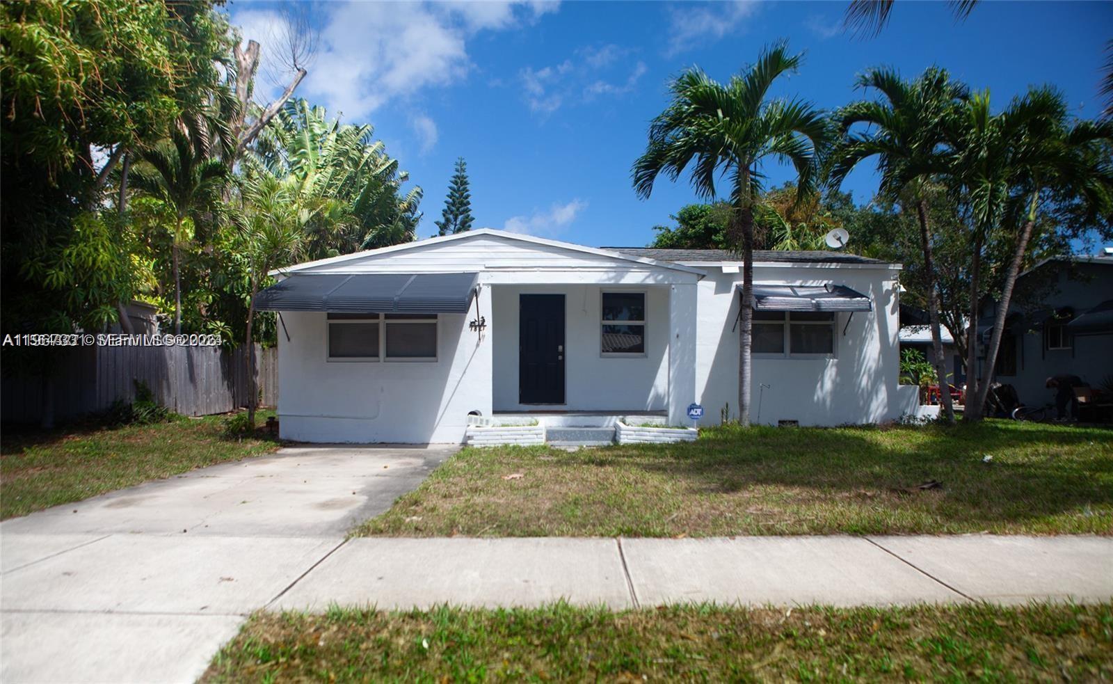 A single-story white house with a dark front door and two metal window awnings — 1821 Harding St, Hollywood FL 33020, HOLLYWOOD, FL