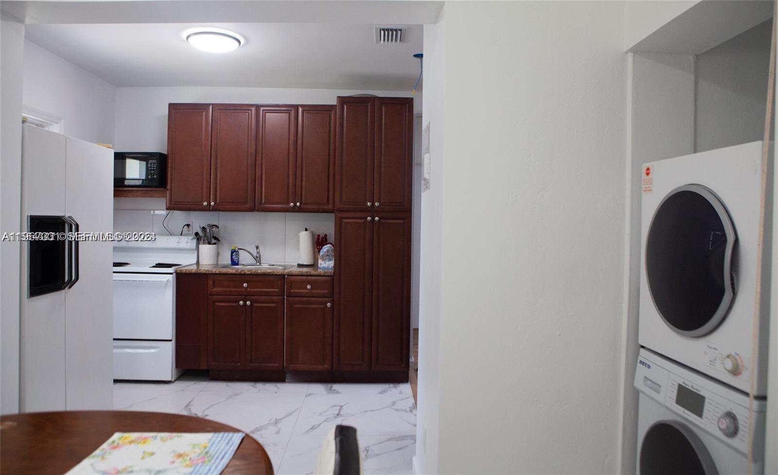 A kitchen with dark wood cabinets, white appliances, and marble-look tile flooring — 1821 Harding St, Hollywood FL 33020, HOLLYWOOD, FL