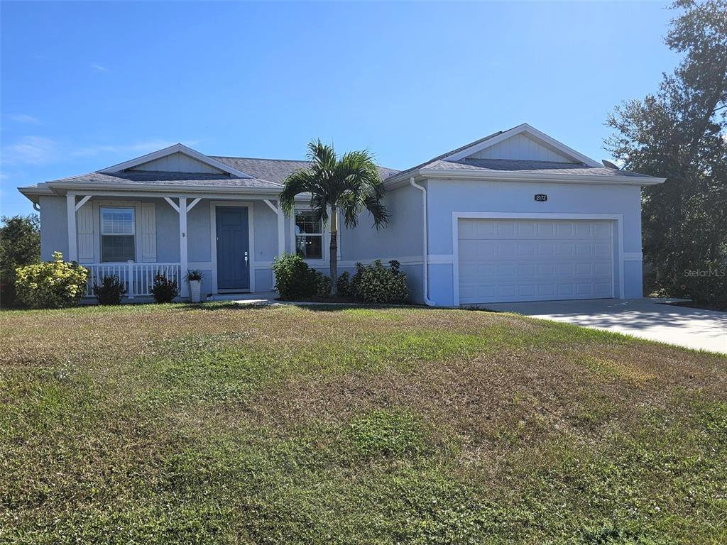 A single-story house with a blue door, a two-car garage, and a palm tree — 2172 PEASLEY STREET, PORT CHARLOTTE, FL