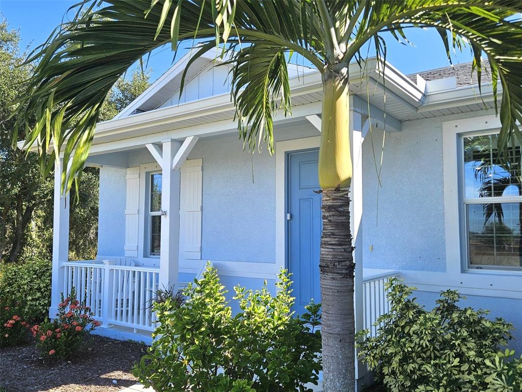 A light blue house features a front porch, white railings, and a palm tree — 2172 PEASLEY STREET, PORT CHARLOTTE, FL