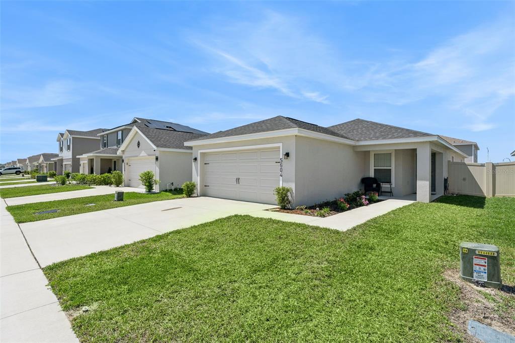 A single-story suburban house with a two-car garage and a small front yard — 5604 MADDIE DRIVE, HAINES CITY, FL