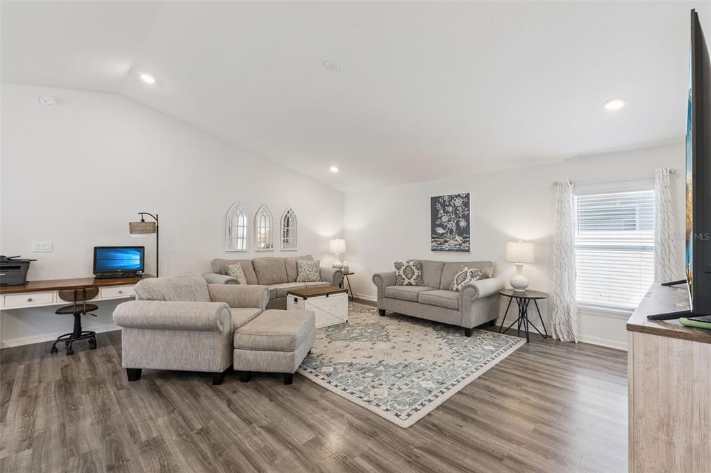 A living room features gray furniture, a patterned area rug, and a built-in desk area — 5604 MADDIE DRIVE, HAINES CITY, FL