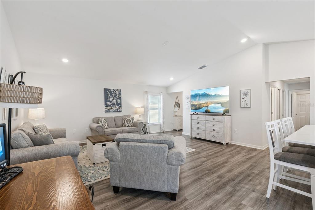 A living room features gray furniture, wood-look flooring, and a television mounted on a dresser — 5604 MADDIE DRIVE, HAINES CITY, FL