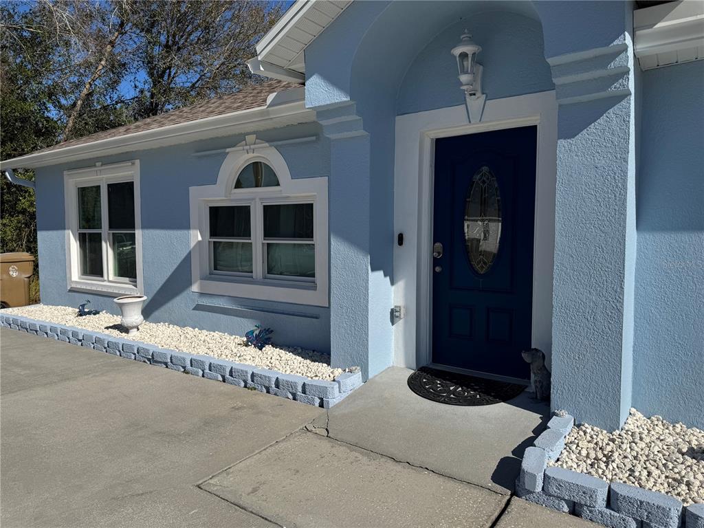 The exterior of a light blue house features a dark blue front door and white trim — 303 BACCARAT COURT, KISSIMMEE, FL