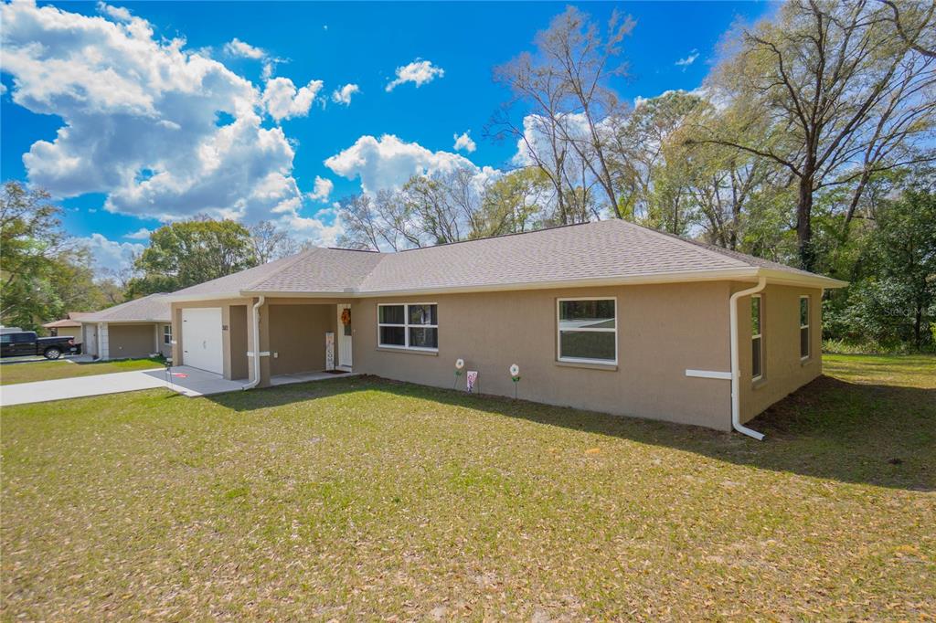 A tan, single-story house with a shingled roof, garage, and front yard under a blue sky — 3522 S OAKDALE TERRACE, INVERNESS, FL