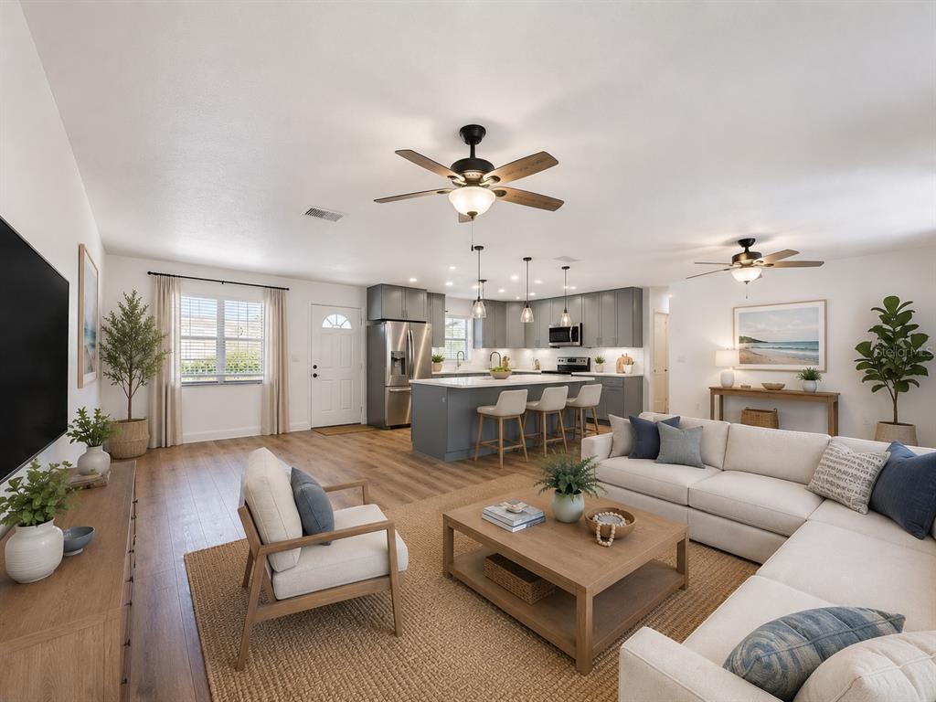 An open-concept living room and kitchen featuring a large island, gray cabinetry, and wood flooring — 2188 CORINNE COURT S UNIT A, ST PETERSBURG, FL