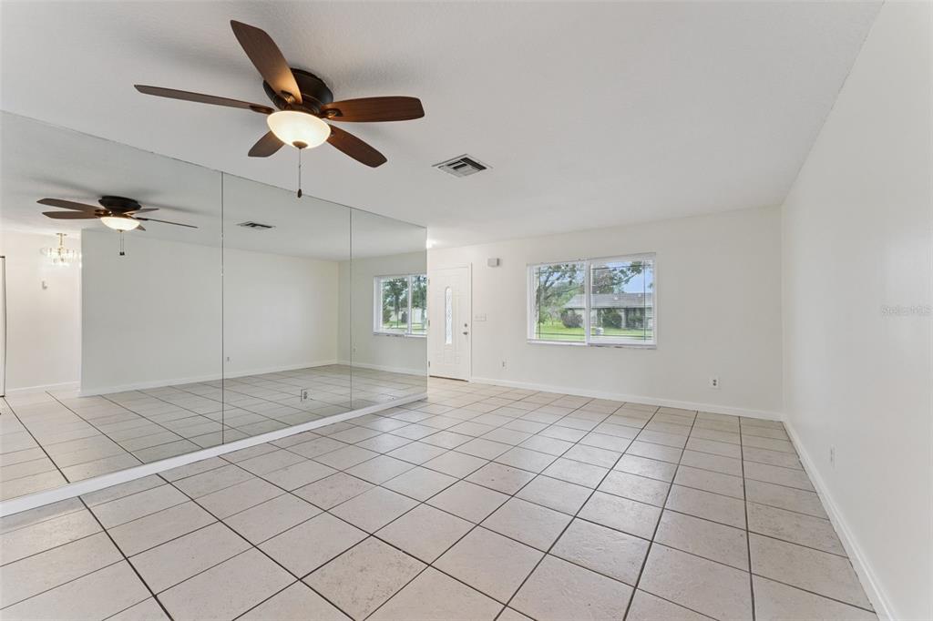 A room with tiled floors, a ceiling fan, and a large mirrored wall — 2142 KENDALL COURT, DELTONA, FL