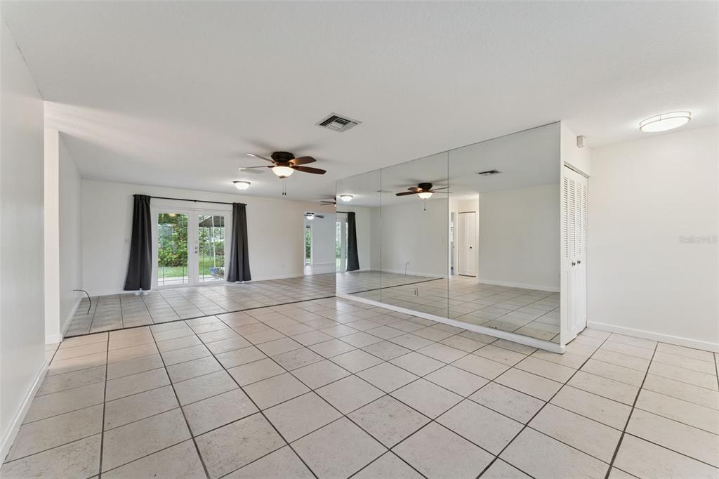 A living room features light-colored tile flooring, a mirrored wall, and glass sliding doors — 2142 KENDALL COURT, DELTONA, FL