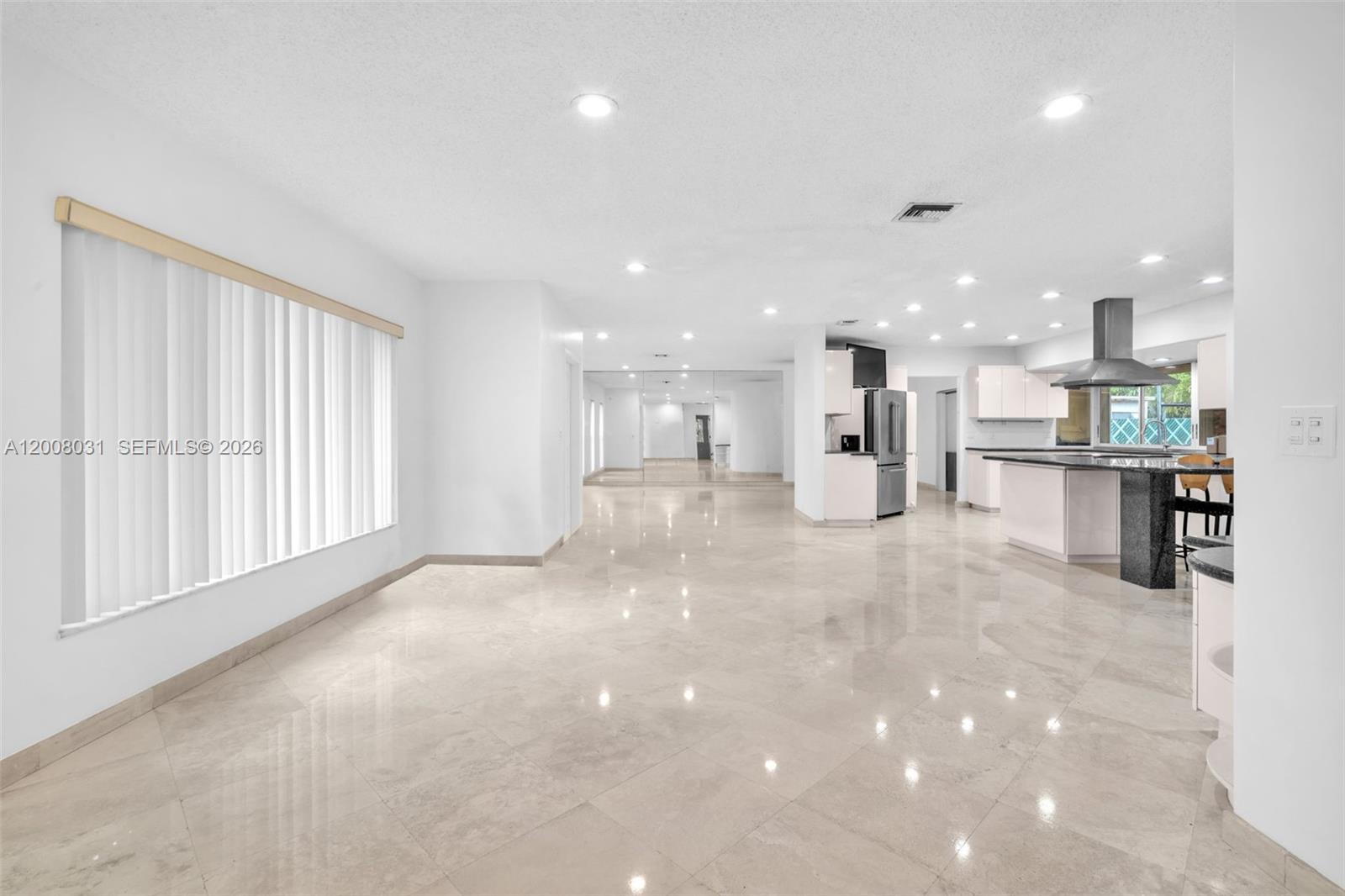 A bright, open-concept living area features polished tile flooring, white walls, and a mirrored wall — 3441 N Hills Dr # 00, Hollywood FL 33021, HOLLYWOOD, FL