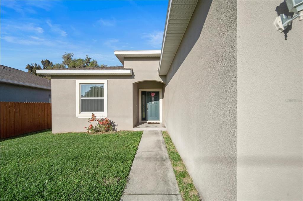 A concrete walkway leads to the front entrance of a single-story house with stucco siding — 14 FERGUSON DRIVE, ORLANDO, FL