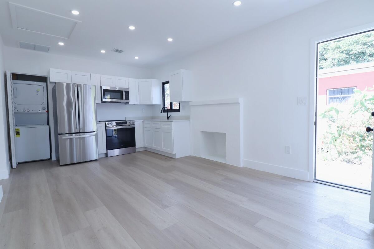 A modern kitchen features white cabinets, stainless steel appliances, and light wood flooring — 3040 NW 13th Avenue # 1, Miami FL 33142, MIAMI, FL