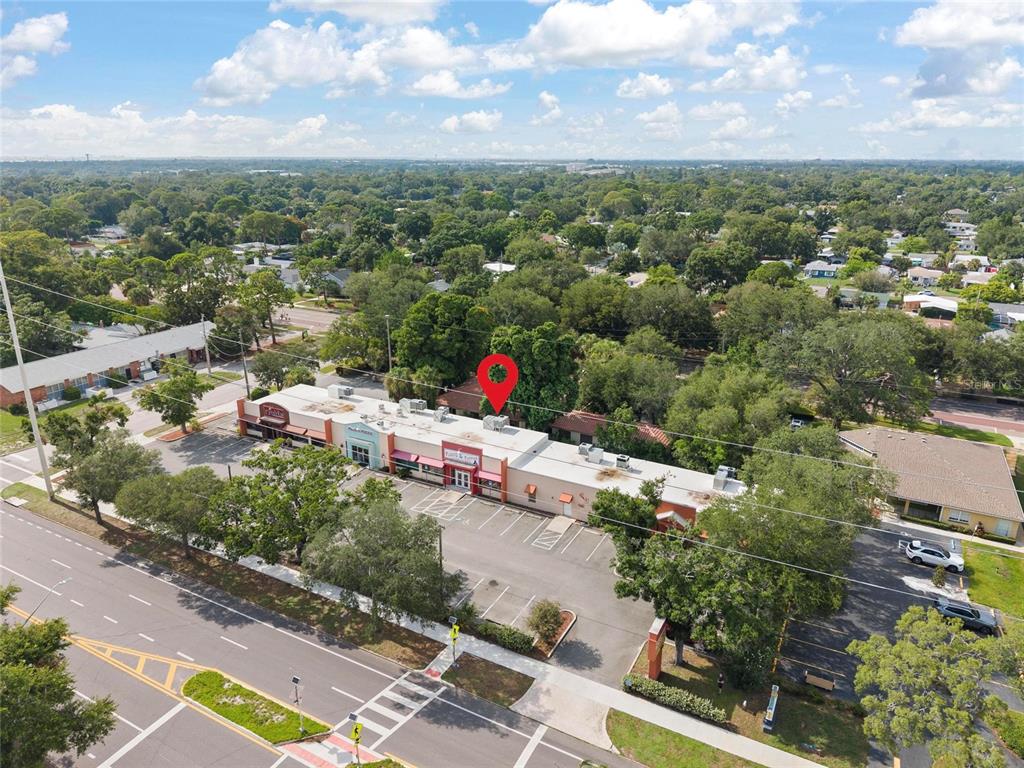 An aerial view shows a commercial strip mall with a parking lot and surrounding trees — 6295 CENTRAL AVENUE, ST PETERSBURG, FL