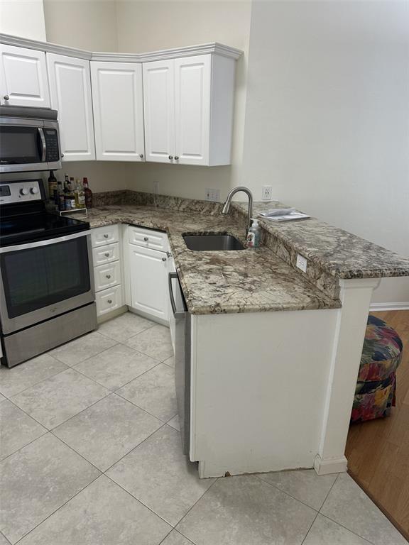 A kitchen features white cabinets, granite countertops, stainless steel appliances, and tile flooring — 5202 SW 91ST TERRACE UNIT B, GAINESVILLE, FL
