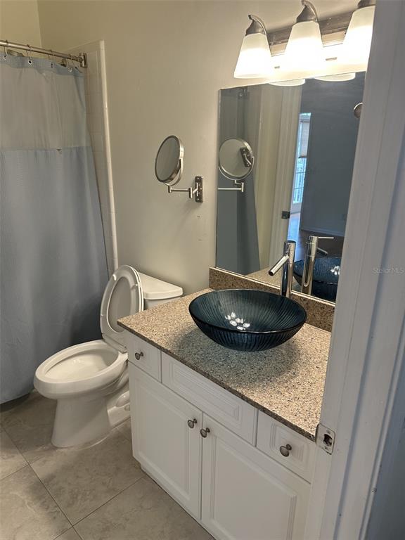 A bathroom features a white vanity with a blue vessel sink and a wall-mounted mirror — 5202 SW 91ST TERRACE UNIT B, GAINESVILLE, FL