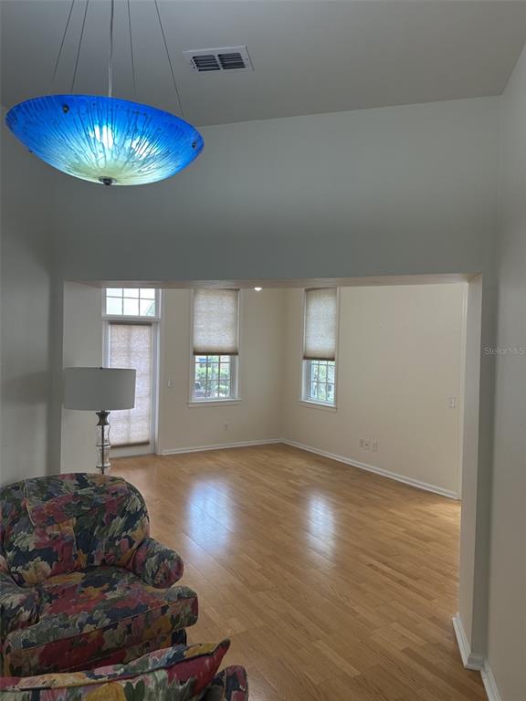 A floral armchair sits in the foreground of a room with hardwood floors and windows — 5202 SW 91ST TERRACE UNIT B, GAINESVILLE, FL