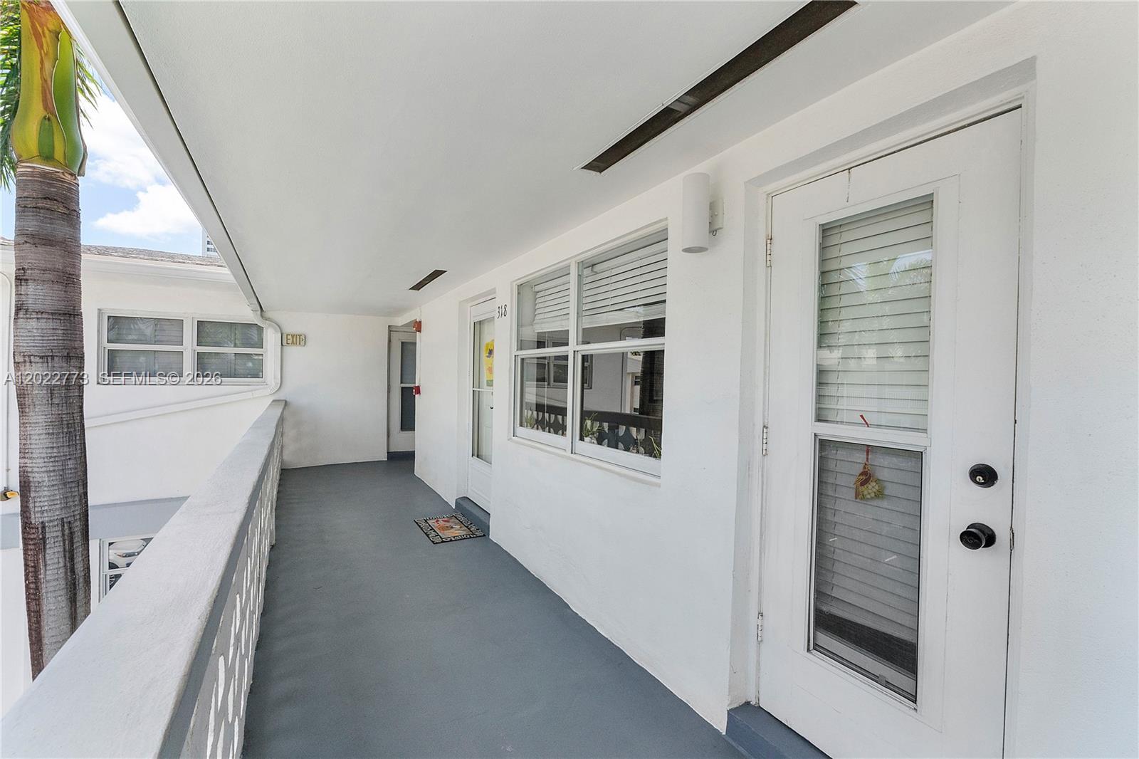 An exterior walkway features white walls, a gray floor, and doors to residential units — 3133 S Ocean Dr # 318, Hallandale Beach FL 33009, HALLANDALE BEACH, FL